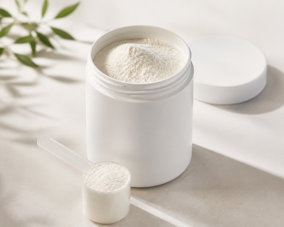Un pot neutre sans étiquette contenant une poudre blanche fine, posé sur une surface claire à côté d'une petite cuillère doseuse.