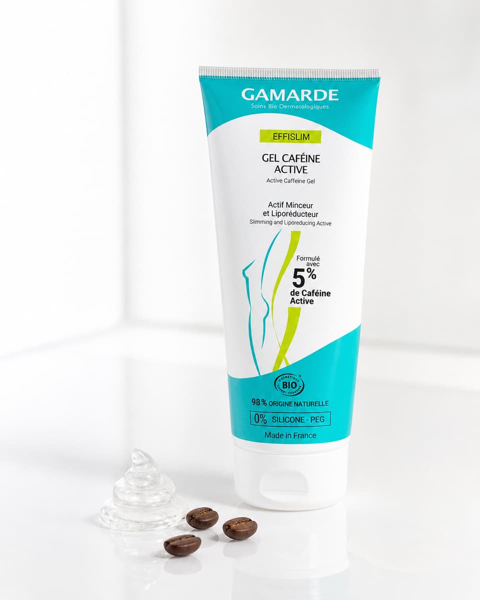 Tube de soin Gamarde Effislim présenté debout sur un plan clair à côté d'une noisette de gel translucide et de quelques grains de café.